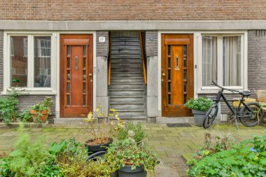 Amsterdam, Hollanda - 10 Nisan 2021: Kapının önünde saksılar ve bitkiler olan bir dış alan, kaldırıma birkaç bisiklet park edilmiş.