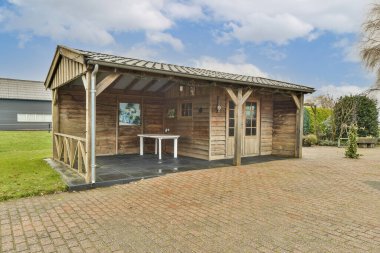 Masası, sandalyeleri ve şemsiyeleri olan ahşaptan yapılmış ahşap bir binanın önünde.