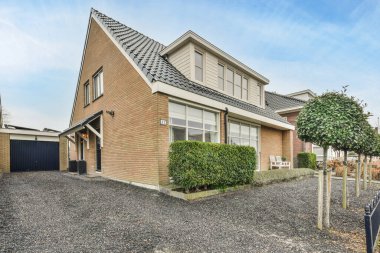 Amsterdam, Hollanda - 10 Nisan 2021: Evin her iki tarafında da çakıl ve çalılar olan bir evin ortasında mavi bir gökyüzü var.