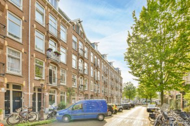 Sokak kenarına park etmiş birkaç bisiklet. Pencereleri ve kapıları olan tuğladan apartmanların önünde.