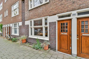 Amsterdam, Hollanda - 10 Nisan 2021: Her iki tarafında iki kapısı ve önünde park etmiş bir bisikleti olan açık kapısı olan tuğla bir bina