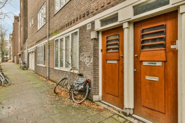 Amsterdam, Hollanda - 10 Nisan 2021: Üzerinde grafiti yazan eski bir tuğla binanın önündeki caddenin kenarına park edilmiş iki bisiklet