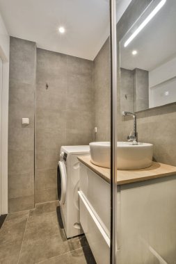 Tuvaleti, lavabosu ve aynası olan bir banyo. Sağ taraftaki duş kabinine kadar.