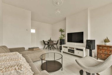 Oturma odası, koltuklar, sandalyeler ve odanın ortasındaki duvarda düz ekran televizyon.