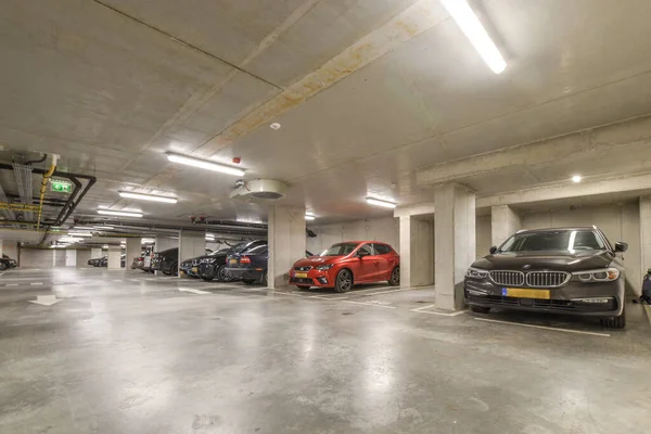 stock image an underground parking area with cars parked in the space and people walking on the sidewalk to get their car keys