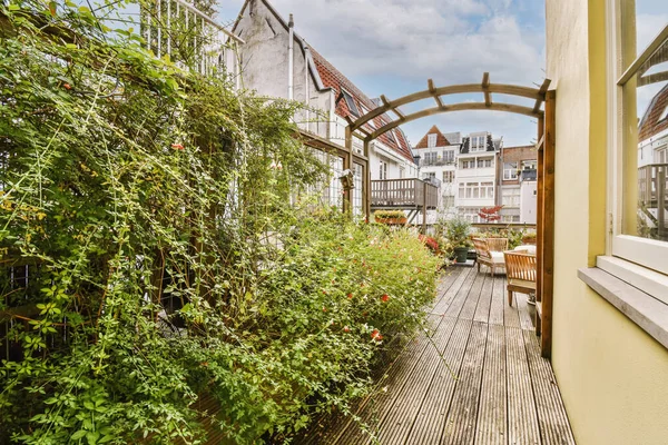 Stock image a balcony with plants growing on the wall and wooden flooring in front of the house, taken from outside