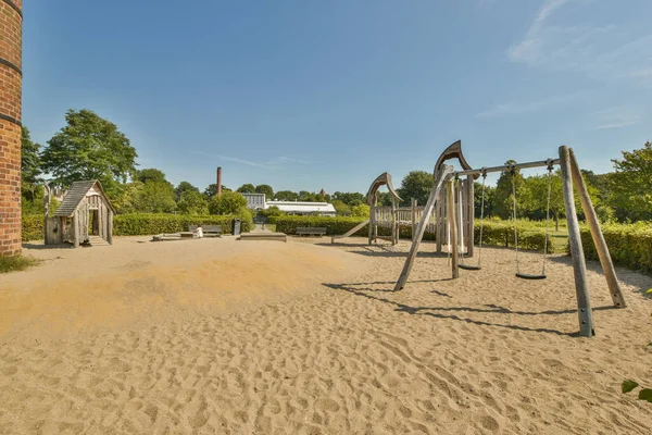 子供が遊ぶためのスイング スライド スライドを備えた公園の真ん中にある空の遊び場 — ストック写真