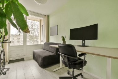 TV 'nin önündeki duvarda kanepesi, sandalyesi ve bilgisayar monitörü olan bir oturma odası.