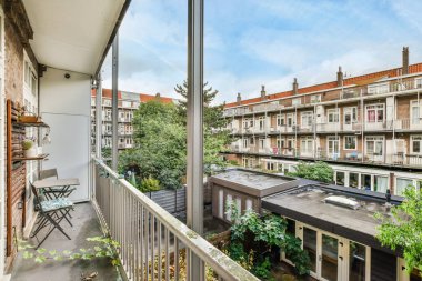 Amsterdam, Hollanda - 10 Nisan 2021: Arka planda bazı bitki ve binaların bulunduğu bir balkon, üst kat penceresinden görüldüğü gibi.