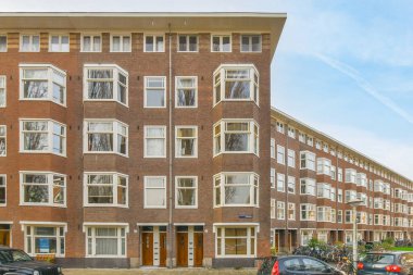 an apartment building with cars parked on the street next to it and people walking down the sidewalk in front of them