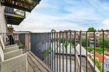 Amsterdam, Hollanda - 10 Nisan 2021: Sol tarafında ahşap banklar ve parmaklıklar olan bir balkon, şehir manzarasına bakıyor.