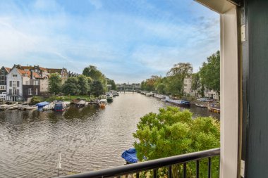 Nehrin diğer tarafındaki evlere ve binalara bakan bir balkondan suya düşen bazı tekneler var.