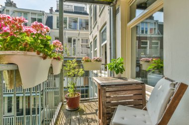 Saksıda çiçekler olan bir balkon ve verandada sokağa bakan boş bir sandalye.
