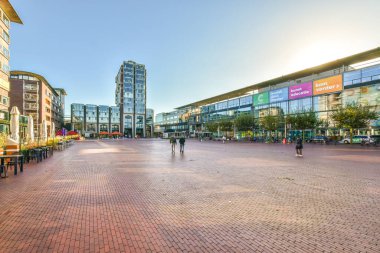 Kaldırımlarda yürüyen insanlarla dolu bir şehir caddesi ve arka planda alçak bir açıdan çekilmiş binalar.