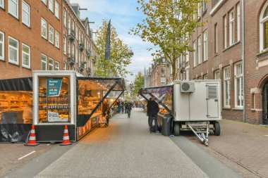 Yolun kenarında çöp kamyonları olan bir cadde ve arka planda yürüyen insanlar.