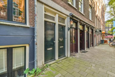 Amsterdam, Hollanda - 10 Nisan 2021: Her iki tarafında binalar ve dükkanların önünde yürüyen insanlar olan bir cadde