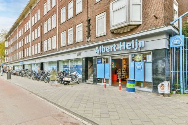 Yolun kenarına parketmiş bisikletli bir cadde ve insanlar binaların önünde kaldırımdan aşağı yürüyor.