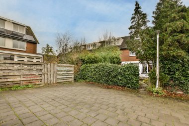 Amsterdam, Hollanda - 10 Nisan 2021: sokağın kenarında, çitlerle çevrili bir evin önünde ağaçların ve çalıların olduğu bir arka bahçe.