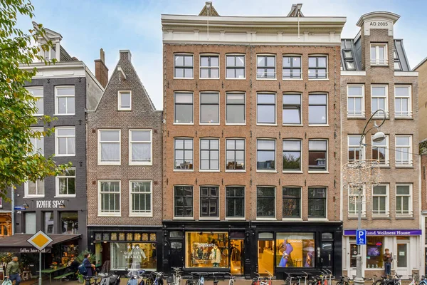 2021年4月10日 荷兰阿姆斯特丹 一些骑自行车在人行道上的人在一幢公寓楼前走来走去 身后是一些建筑物 — 图库照片