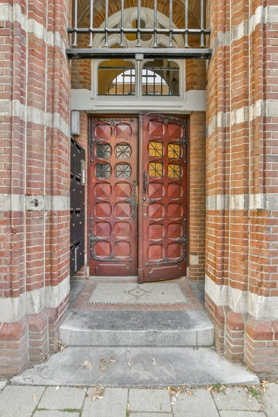 stock image Amsterdam, Netherlands - 10 April, 2021: a brick building with a red door in the middle and an arched window at the top to the doorways