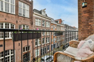 Amsterdam, Hollanda - 10 Nisan 2021: Dışında sandalyeler ve koltuklar olan bir balkon, beyaza boyanmış tuğla bir duvarın önünde