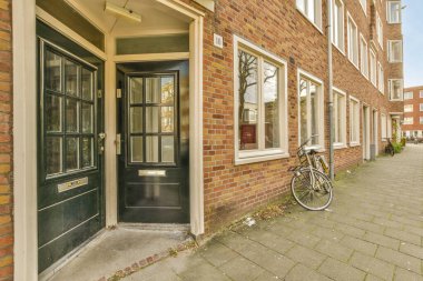 Her iki tarafında iki penceresi ve bir kapısı açık olan tuğla bir binanın önüne park edilmiş bir bisiklet.