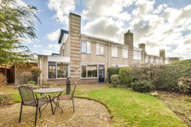 Bahçenin ortasında ağaçlar ve çalılarla çevrili masa ve sandalyeler olan bir alan.