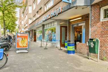 Amsterdam, Hollanda - 10 Nisan 2021: Meyve suyu reklamı olan bir tuğla binanın önündeki caddenin kenarına park edilmiş bir bisiklet