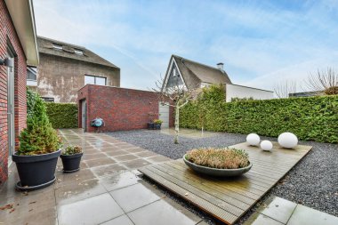 Amsterdam, Hollanda - 10 Nisan 2021: Bahçenin diğer tarafında iki tencere ve ortasında bitkiler olan bir arka bahçe alanı, mavi bir gökyüzü var.