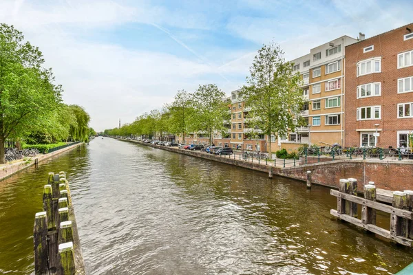 Amsterdam, Hollanda - 10 Nisan 2021: Kentin ortasında bir kanal, her iki tarafında binalar ve bisikletlerle yan yana park edilmiş.