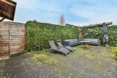 Amsterdam, Hollanda - 10 Nisan 2021: ahşap bir arka bahçe duvarının önünde birkaç sandalye ve bitki bulunan bir arka bahçe alanı