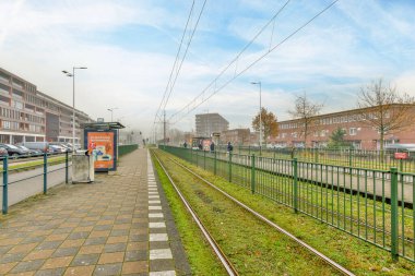 Amsterdam, Hollanda - 10 Nisan 2021: Raylarda arabaları olan bir tren istasyonu ve yolda yürüyen insanlar boş bir caddedir.