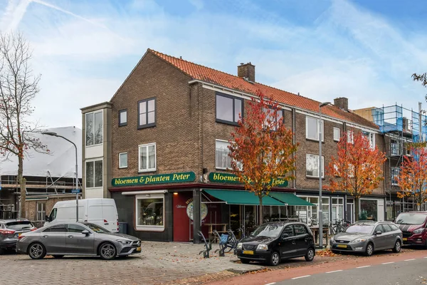 stock image a city street with cars parked in front of buildings and trees that are turning to red leaves on the ground