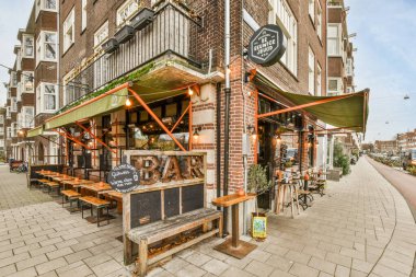 Amsterdam, Hollanda - 10 Nisan 2021: Eski bir tuğla binanın önündeki kaldırımda masaları ve bankları olan bir restoranın dışı