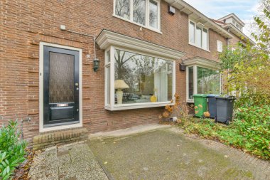 Amsterdam, Hollanda - 10 Nisan 2021: Duvarları tuğlalı ve camları beyaz süslemeli bir evin dış görünüşü