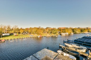 Nehrin diğer tarafındaki bazı tekneler ve binalar üzerlerinde mavi gökyüzü vardı.