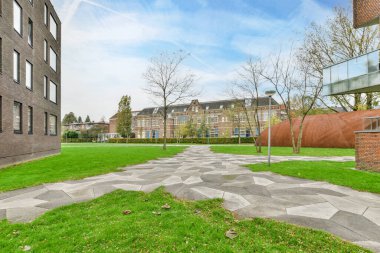 Amsterdam, Hollanda - 10 Nisan 2021: Sokağın her iki tarafında ağaçlar ve binalar olan bir apartmanın ortasında çimenli bir alan