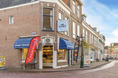 Fotoğrafın ortasında dükkanları ve restoranları olan küçük bir kasaba sokağı güneşli bir günde çekilir.