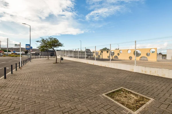 stock image a brick paved street in the middle of an urban area with buildings and trees on both sides, under a blue sky