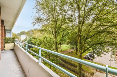 Amsterdam, Hollanda - 10 Nisan 2021: Ağaçların ve arabaların olduğu bir apartman balkonunda ön tarafa park edilmiş bir resim çekilmiştir.