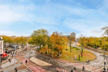 Şehrin ortasında bir kavşakta insanların yürüdüğü, bisikletin sürdüğü ve arabaların geçtiği bir kavşak.