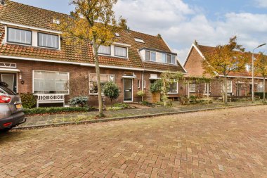 Önlerine arabaları park edilmiş bazı evler ve evin yanına park edilmiş bir araba var.