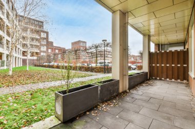 Amsterdam, Hollanda - 10 Nisan 2021: Etrafı binalarla çevrili bir binanın önünde ağaçlar ve yapraklarla çevrili bir dış alan