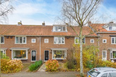 Amsterdam, Hollanda - 10 Nisan 2021: Garaj yoluna park edilmiş bazı evler ve diğer iki binanın yanına park edilmiş bir araba