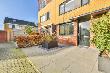 Önünde saksılar olan bir evin dışında ve binaya giriş kapısı kırmızı tuğladan yapılmıştır.