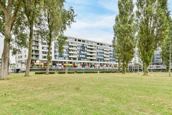 stock image Amsterdam, Netherlands - 10 April, 2021: an apartment complex with trees and grass in the fore - image is taken from the ground looking towards to the building