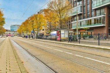 Amsterdam, Hollanda - 10 Nisan 2021: kaldırımlarda yürüyen insanların ve arka planda binaların olduğu bir şehir caddesi, hareket halindeki bir trenden alındı
