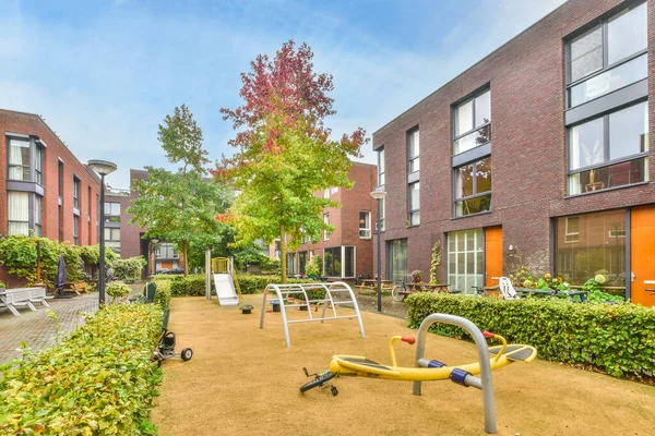 Amsterdam, Hollanda - 10 Nisan 2021: Bahçenin her iki tarafında da bir sürü ağaç ve çalılık olan yerleşim yerinin ortasında boş bir oyun alanı