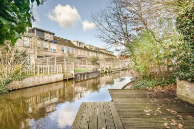 Nehrin ortasındaki ahşap rıhtımda her iki tarafında evler ve sular boyunca büyüyen ağaçlar var.