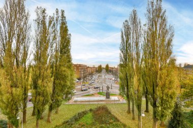 Masmavi gökyüzü ve beyaz bulutların üzerinde güneşli bir günde şehrin ortasındaki bazı ağaçlar.